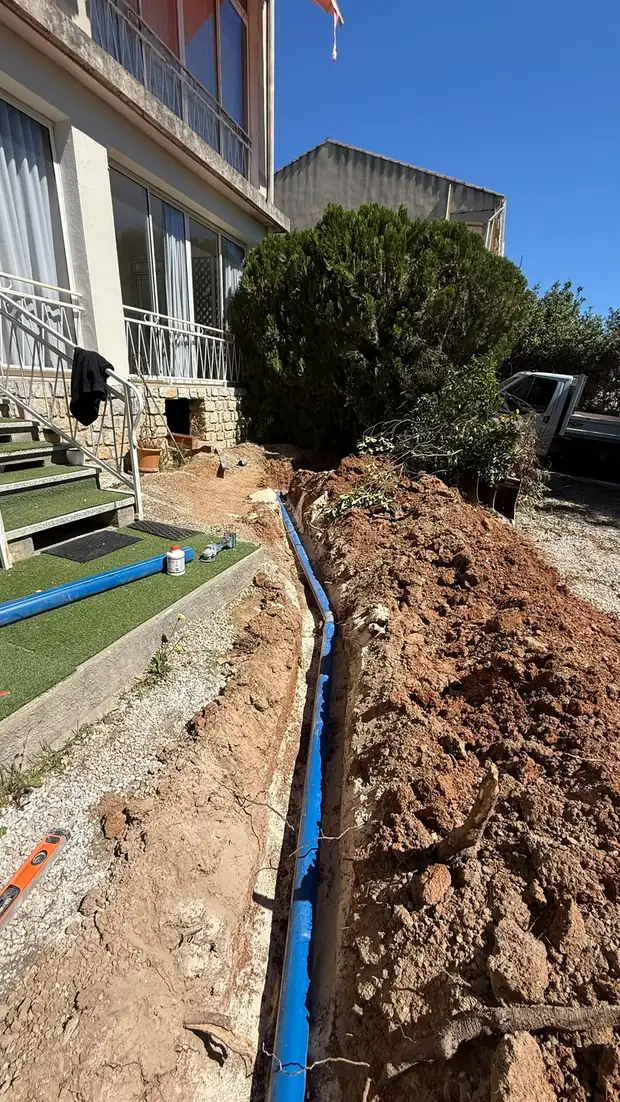 Tranchée et pose de canalisation le long d'une maison